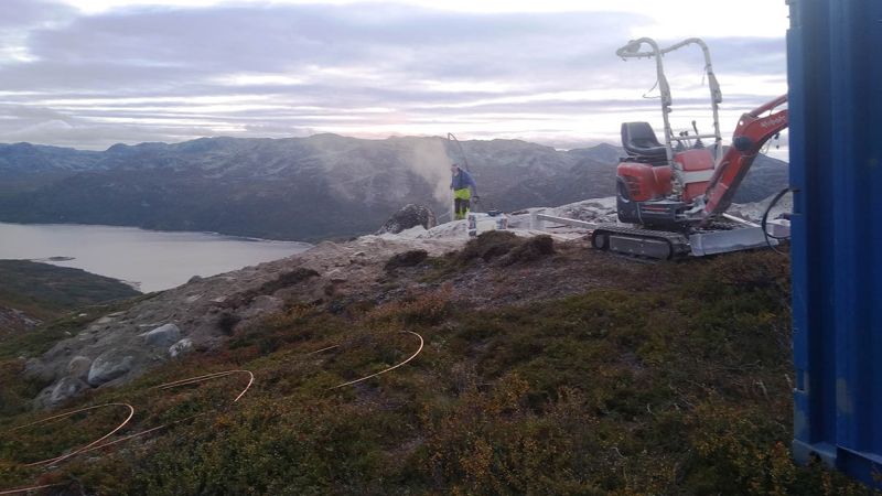 oppføring av telemast og hytte på fjellet med fjord i bakgrunn