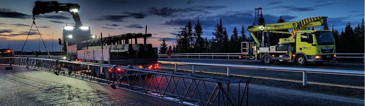 to kranbiler i solnedgang på bilvei klar for montering av portal