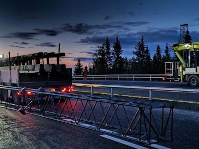 to kranbiler i solnedgang på bilvei klar for montering av portal