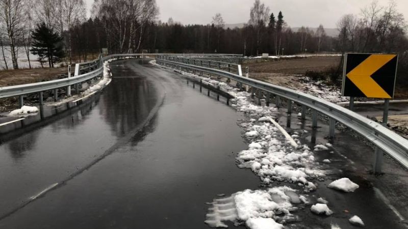 våt bilvei over bro med litt snø i kanten