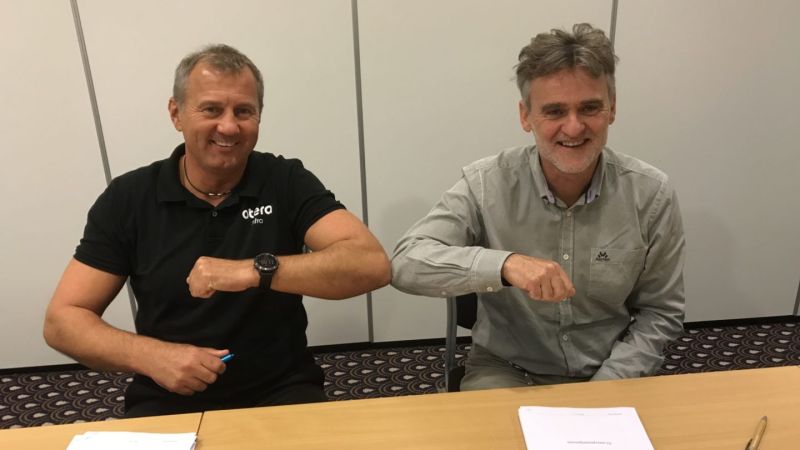 to menn håndhilser med albuen etter signert kontrakt