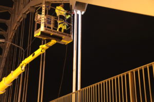 elektriker i krankurv sjekker lys på bro